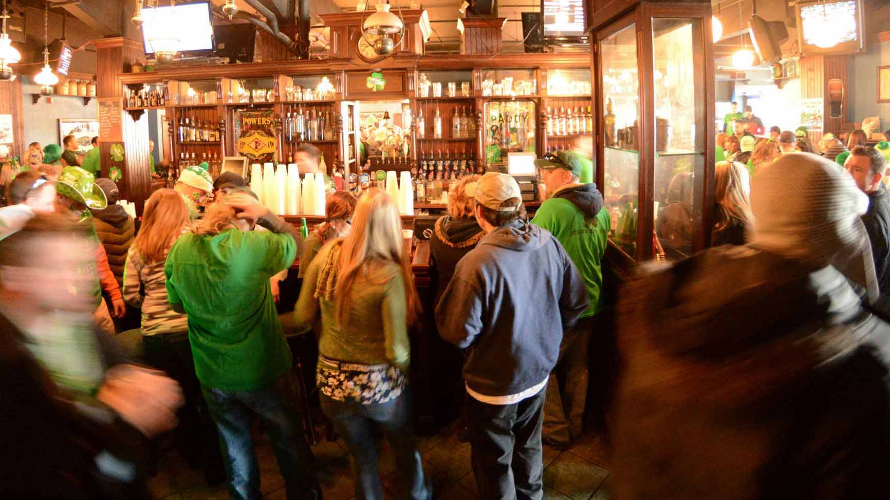 Patrons wearing green share drinks around an Irish pub in Buffalo, NY.